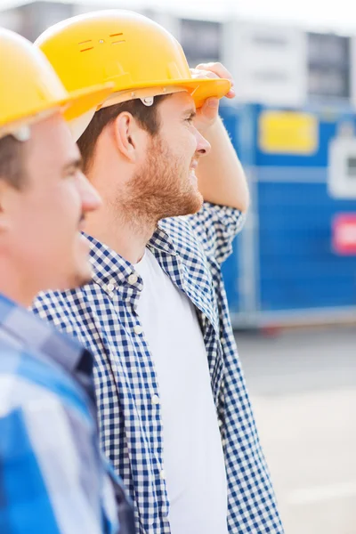 Groep van lachende bouwers in hardhats in openlucht — Stockfoto