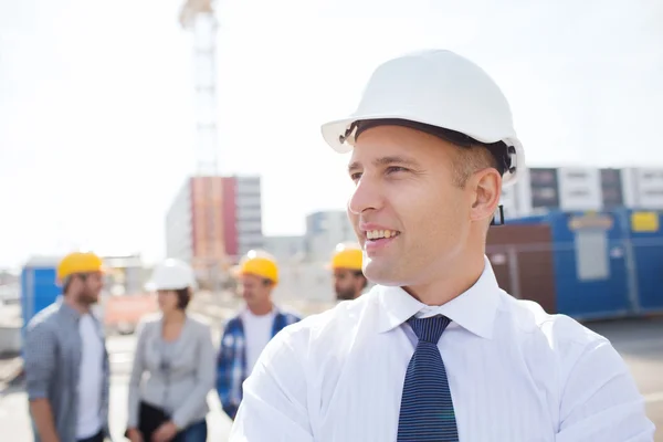 Grupa budowniczych uśmiechający się w hardhats na zewnątrz — Zdjęcie stockowe