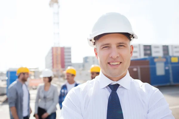 Grupa budowniczych uśmiechający się w hardhats na zewnątrz — Zdjęcie stockowe