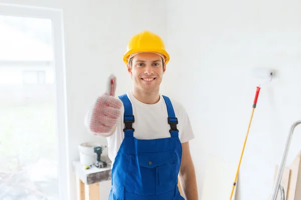 Smiling young builder in hardhat showing thumbs up — Stock Photo, Image