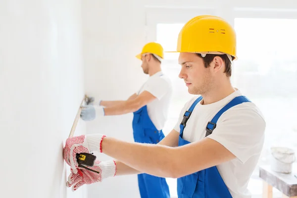 Group of builders with measuring tape indoors — Stock Photo, Image