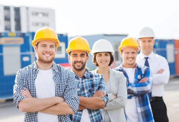 Gruppo di costruttori sorridenti in hardhats all'aperto — Foto Stock