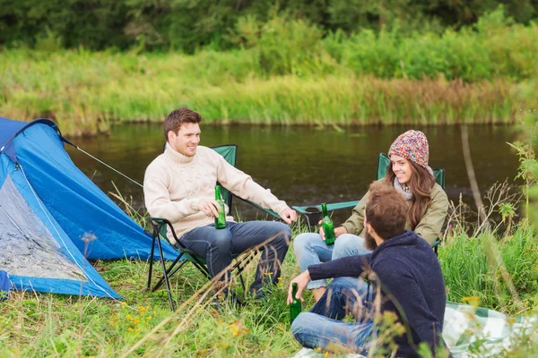 Group of smiling tourists drinking beer in camping Stock Picture