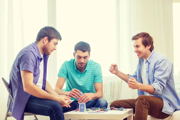 Felizes três amigos do sexo masculino jogando poker em casa — Fotografia de Stock