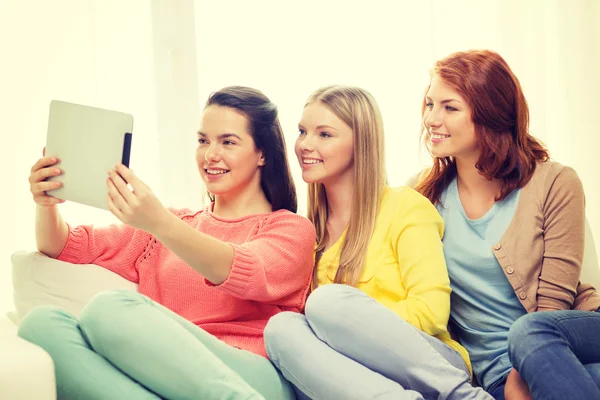 Trzy uśmiechnięte nastolatki z tabletem w domu — Zdjęcie stockowe