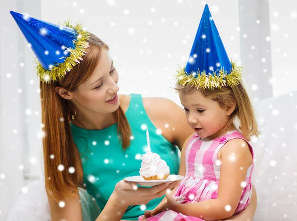 Mother and daughter in party hats with cake — Stock Photo, Image