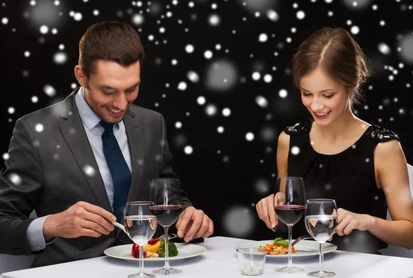 Sonriente pareja comiendo plato principal en restaurante — Foto de Stock