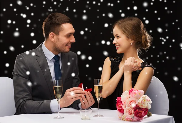 Casal sorridente com caixa de presente vermelho no restaurante — Fotografia de Stock