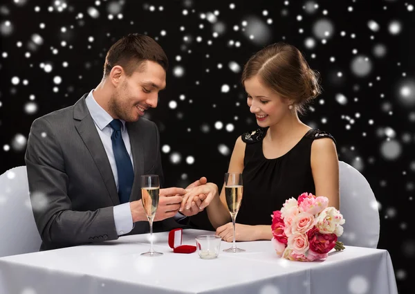 Smiling couple with red gift box at restaurant — Stock Photo, Image