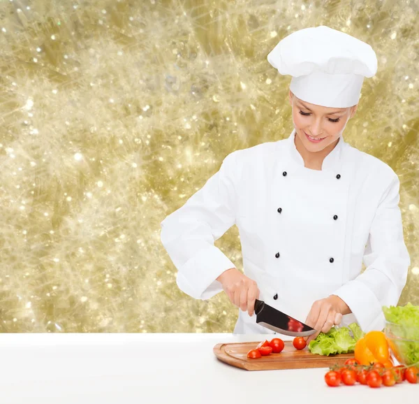 Sorridente chef feminino cortar legumes — Fotografia de Stock