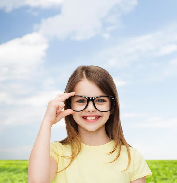 Petite fille mignonne et souriante en lunettes noires — Photo