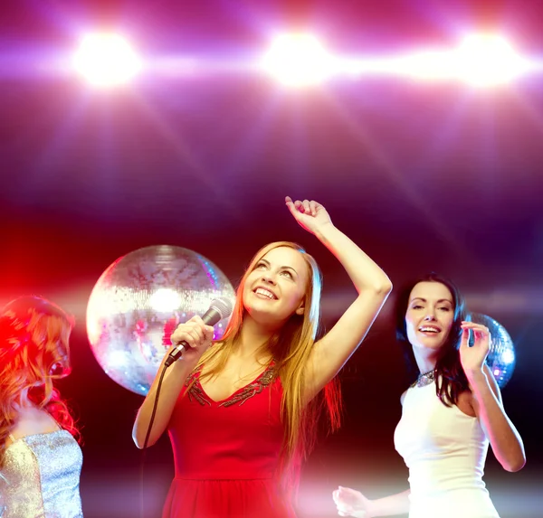 Drie lachende vrouwen dansen en zingen karaoke — Stockfoto