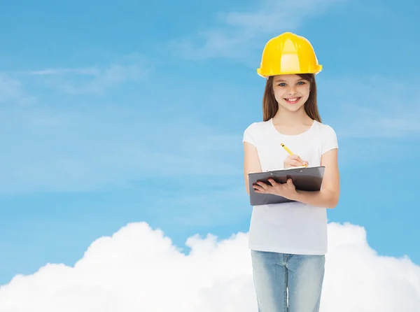 Niña sonriente en hardhat con portapapeles — Foto de Stock