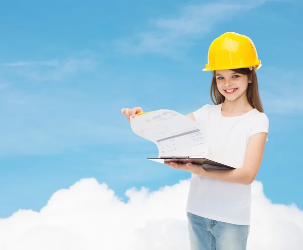 Petite fille souriante en hardhat avec presse-papiers — Photo