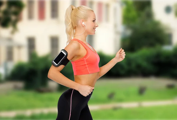Mujer deportiva corriendo con smartphone y auriculares —  Fotos de Stock