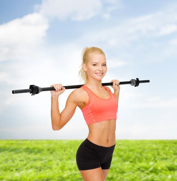 Sorrindo mulher desportiva exercitando com barbell — Fotografia de Stock