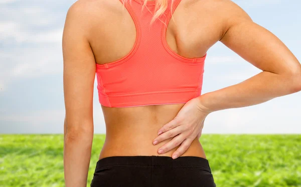 Close up of sporty woman touching her back — Stock Photo, Image