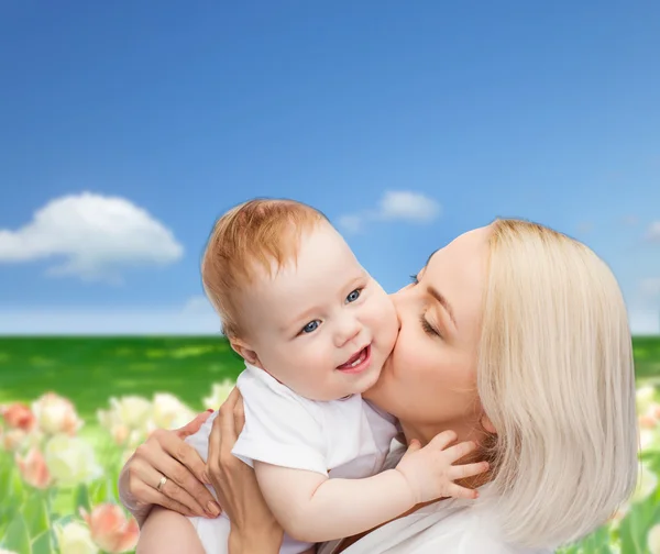 Glückliche Mutter küsst lächelndes Baby — Stockfoto