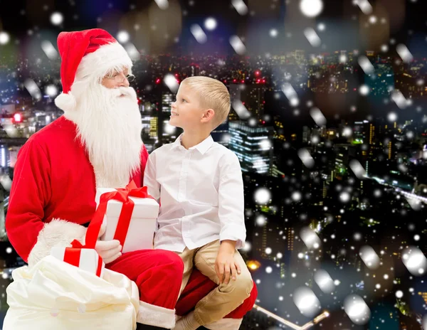 Petit garçon souriant avec santa claus et cadeaux — Photo