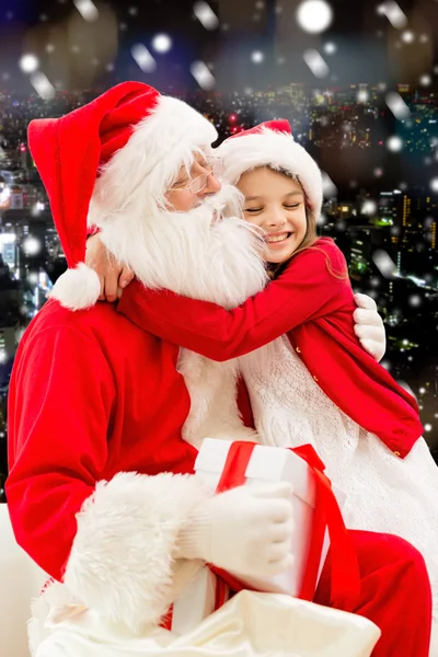 Улыбающаяся маленькая девочка с Санта Клаусом и подарками — стоковое фото