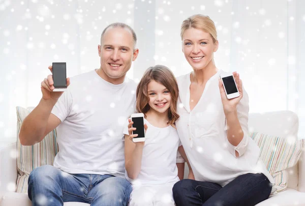 Ευτυχισμένη οικογένεια δείχνει smartphones κενές οθόνες — Φωτογραφία Αρχείου