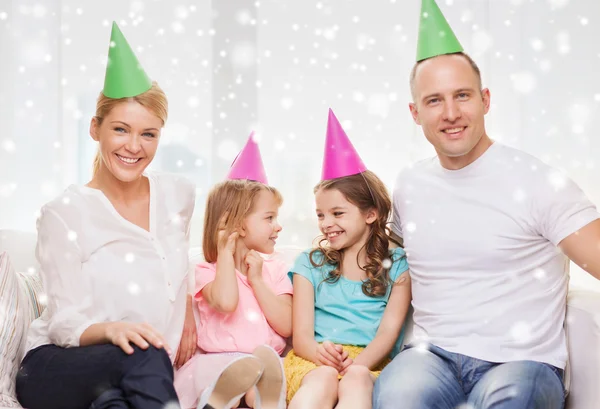 Glückliche Familie mit zwei Kindern in Partyhüten zu Hause — Stockfoto