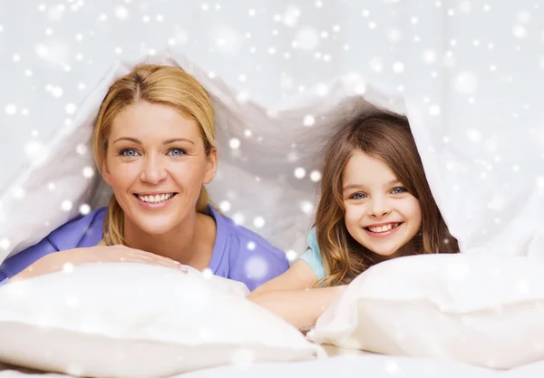 Счастливая мама и девочка под одеялом дома — стоковое фото