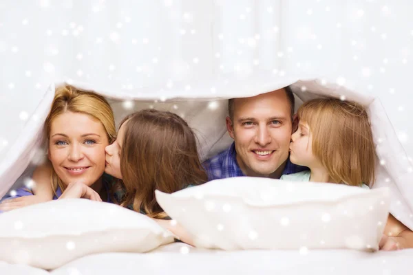 Счастливая семья с двумя детьми под одеялом дома — стоковое фото