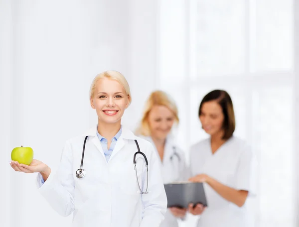 Femme médecin souriante avec pomme verte — Photo