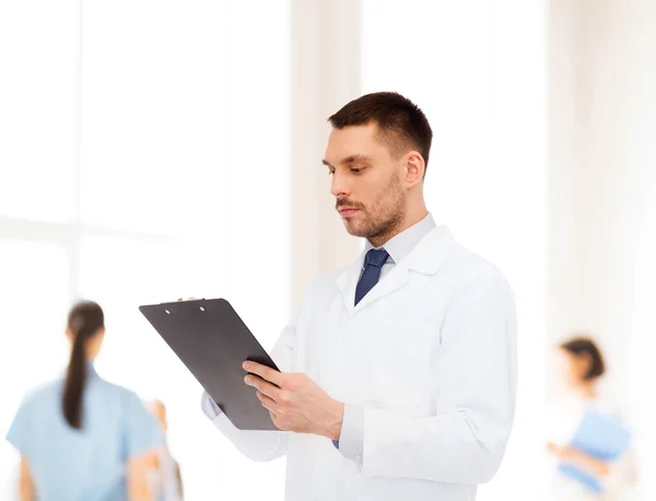 Serious male doctor with clipboard — Stock Photo, Image