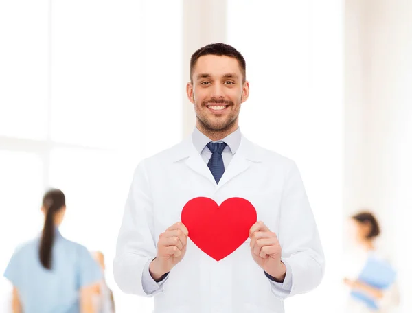 Kırmızı kalp ile gülümseyen erkek doktor — Stok fotoğraf