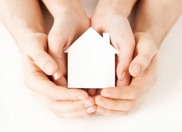 Mains homme et femme avec maison en papier blanc — Photo