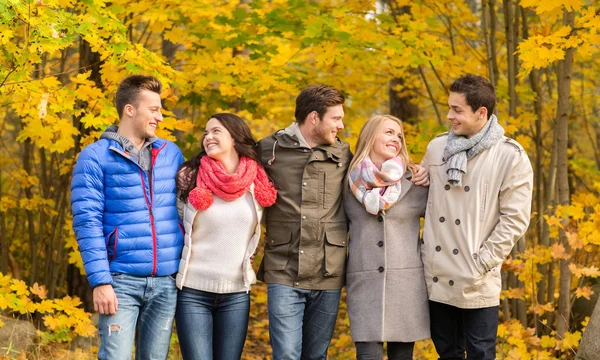 Group of smiling men and women in autumn park — Stock Photo, Image