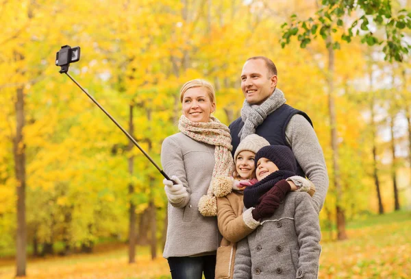 Familia feliz con smartphone y monopod en el parque — Foto de Stock