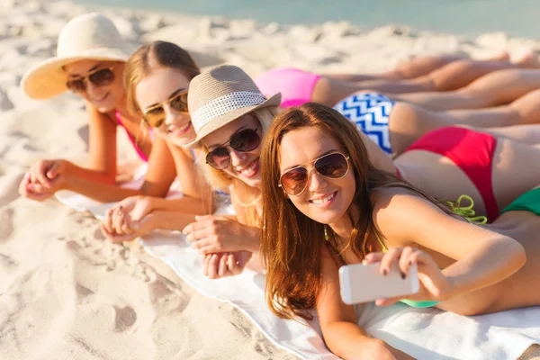 Groupe de femmes souriantes avec smartphone sur la plage — Photo