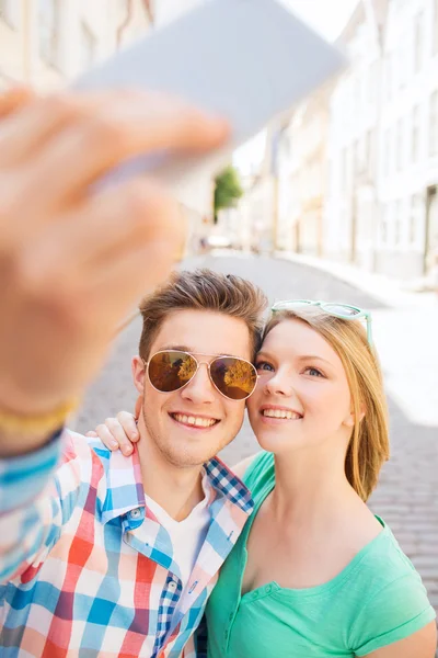 市内でのスマート フォンが付いているカップルの笑みを浮かべてください。 — ストック写真