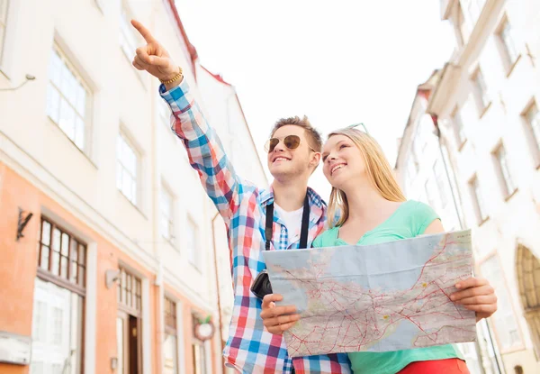 Sonriente pareja con mapa y cámara de fotos en la ciudad — Foto de Stock
