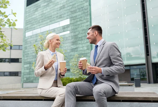 Улыбающиеся бизнесмены с бумажными стаканчиками на открытом воздухе — стоковое фото