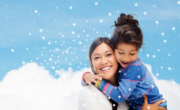 Smiling little girl and mother hugging indoors — Stock Photo, Image