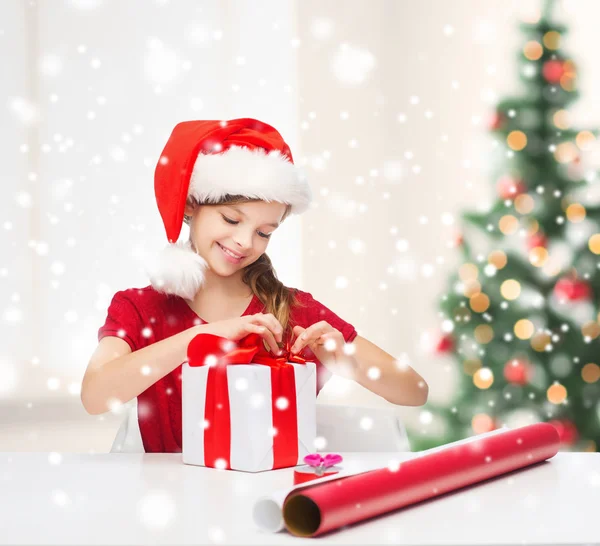 ยิ้มสาวในหมวกผู้ช่วยซานต้ากับกล่องของขวัญ — ภาพถ่ายสต็อก