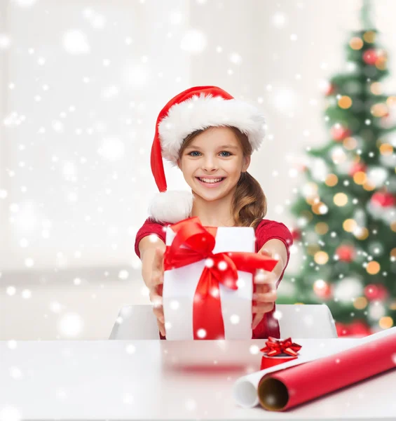 Chica sonriente en sombrero de ayudante de santa con caja de regalo — Foto de Stock