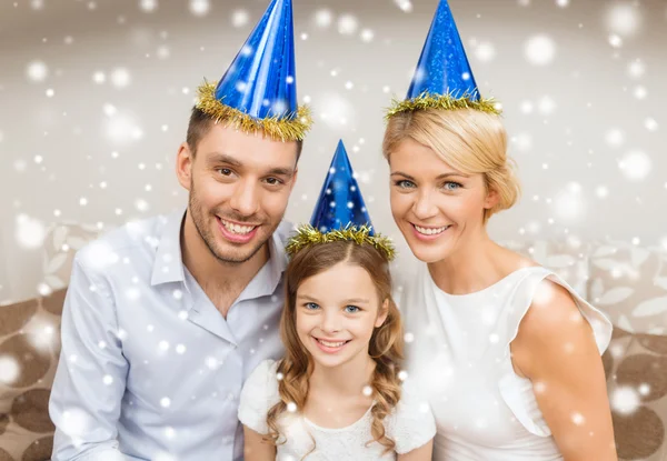 Família sorrindo em chapéus de festa em casa — Fotografia de Stock