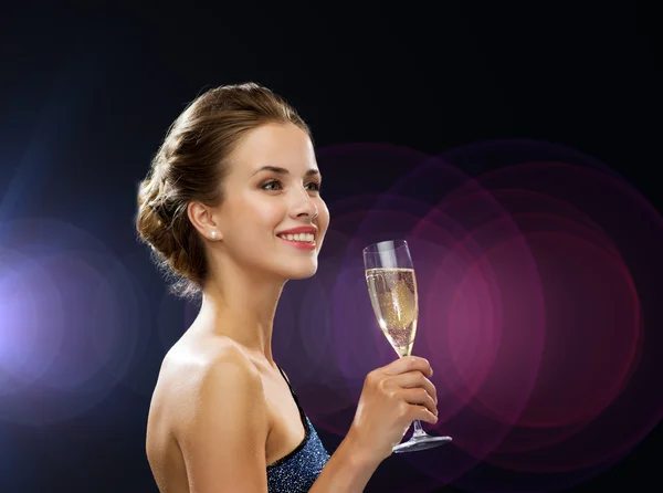 Sonriente mujer sosteniendo un vaso de vino espumoso — Foto de Stock