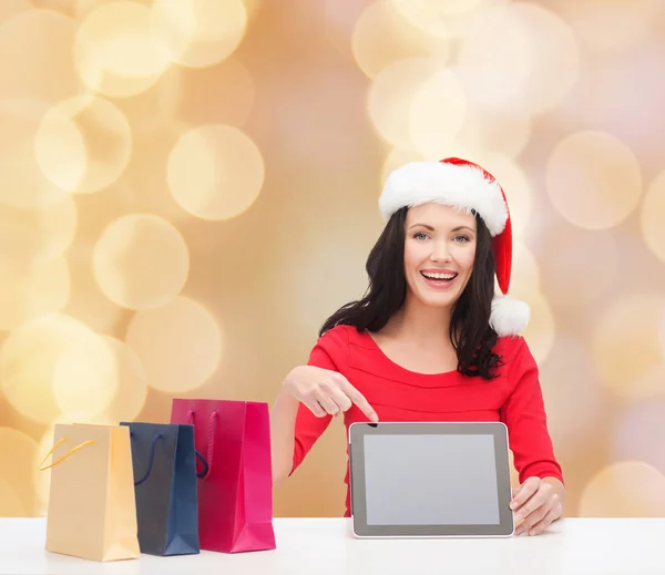Donna sorridente in cappello di Babbo Natale con borse e tablet pc — Foto Stock