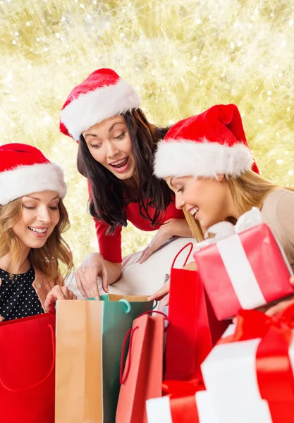 Glimlachen van jonge vrouwen in santa hoeden met geschenken — Stockfoto