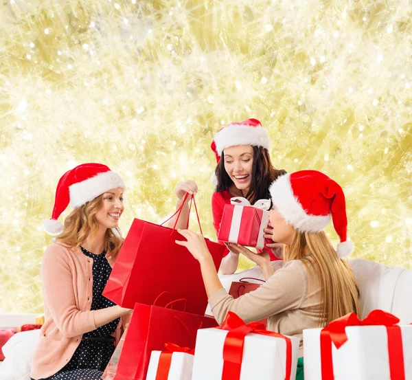 Sorrindo jovens mulheres em chapéus de santa com presentes — Fotografia de Stock