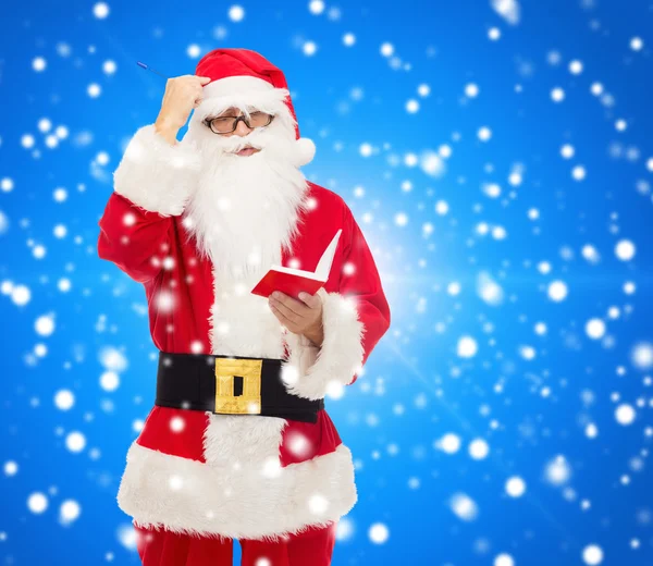 Man in costume of santa claus with notepad — Stock Photo, Image