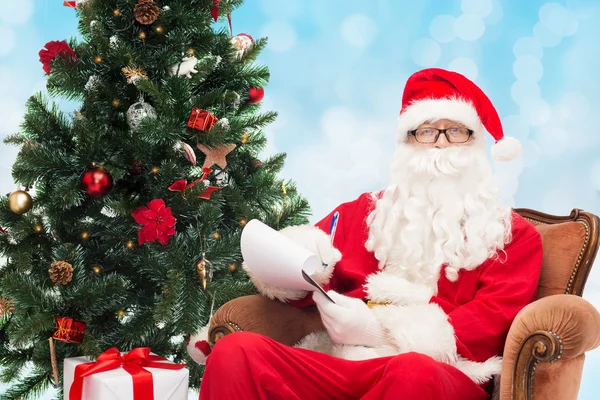 Man in costume of santa claus with notepad — Stock Photo, Image