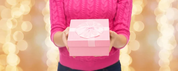 Close up of woman in pink sweater holding gift box — Stock Photo, Image