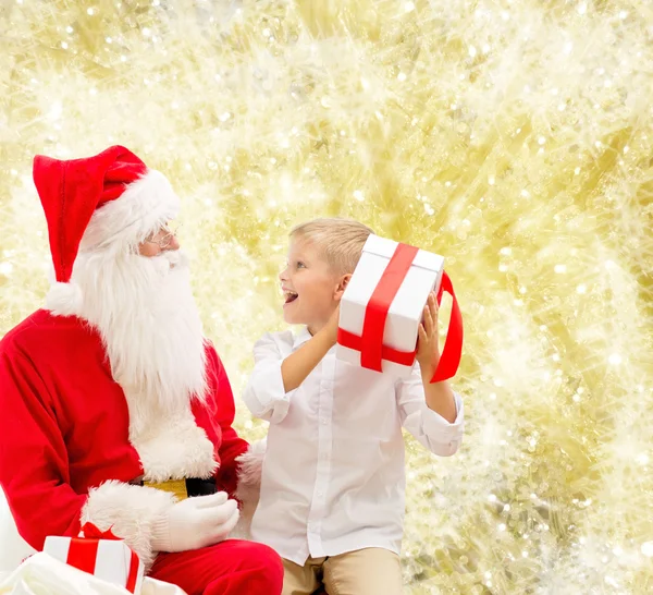 Petit garçon souriant avec santa claus et cadeaux — Photo